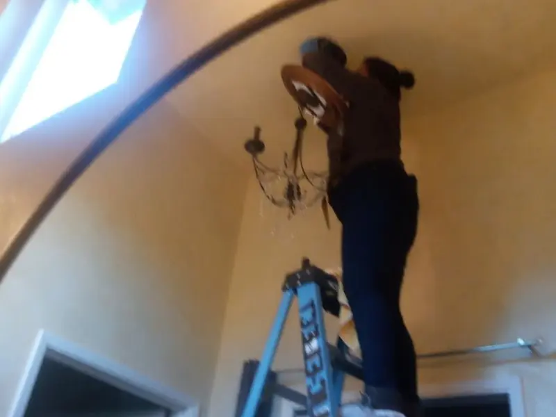 Electrician installing a chandelier in a Hallsville residence